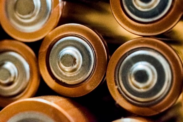 Close-up of the ends of a group of round copper-coloured household batteries.