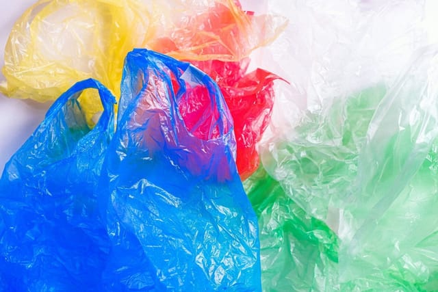 Crumpled thin plastic carrier bags in blue, yellow, red and green.