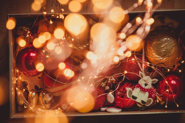 A box of Christmas baubles, ornaments and string lights glowing in the dark.