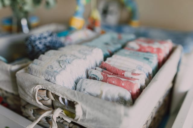Folded cloth nappies arranged in a fabric storage basket.