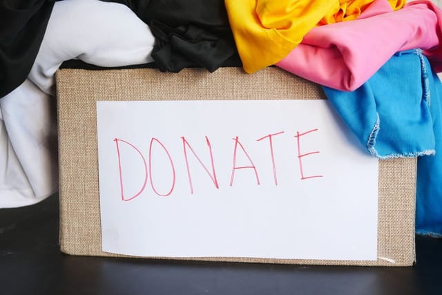 A cardboard box marked DONATE overflowing with folded clothes.
