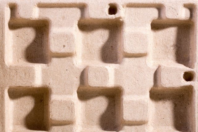 Close-up of moulded paper pulp packaging.