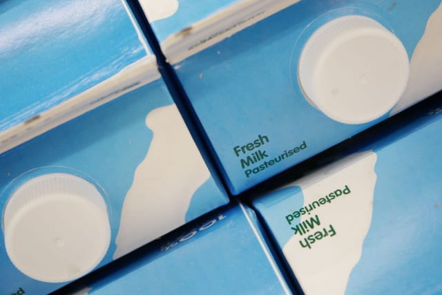 Rows of blue and white milk cartons with plastic screw caps, seen from above.