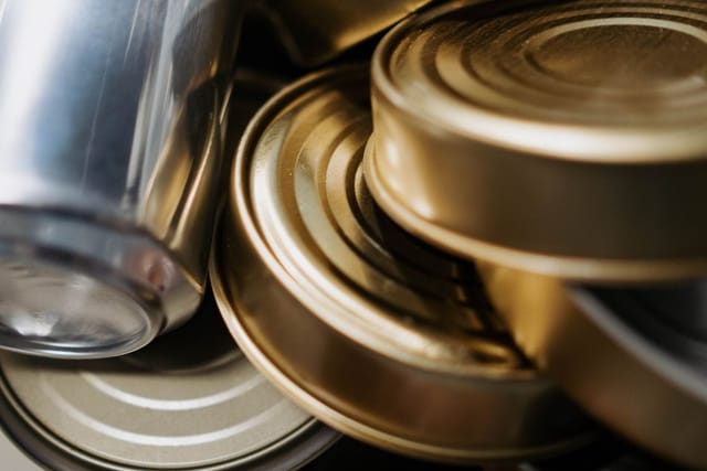 A close-up jumble of empty drink cans and opened food tins.