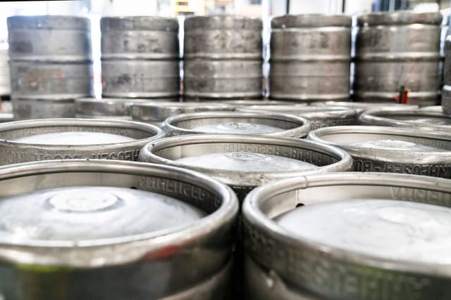 Rows of empty steel beer kegs stacked together.