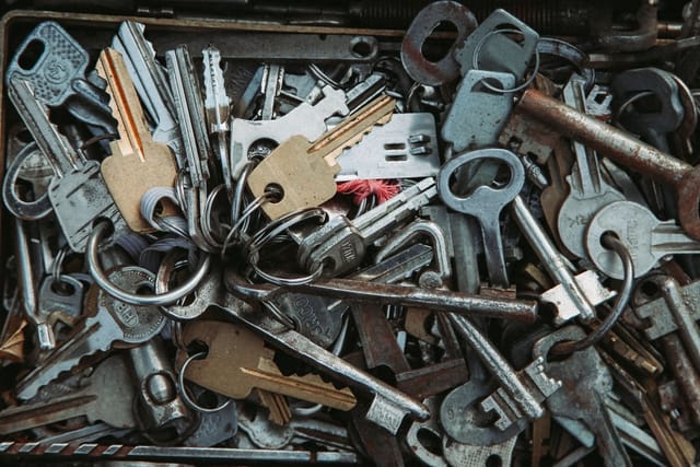 A box full of old metal keys of many shapes, some on key rings.