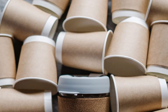 A pile of brown paper takeaway coffee cups with white rims.