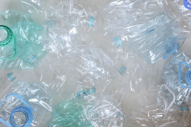 A heap of crushed, empty clear and pale blue plastic bottles seen from above.