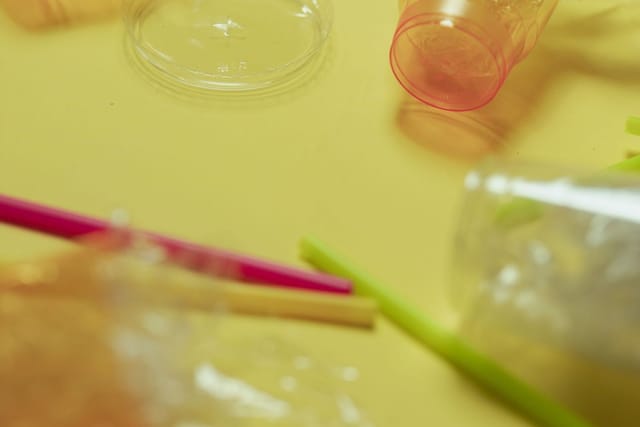 Clear plastic cups, a straw and bubble wrap on a yellow surface.