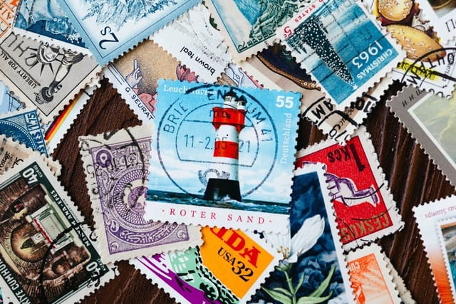 A scatter of colourful used postage stamps from many countries on a wooden table.