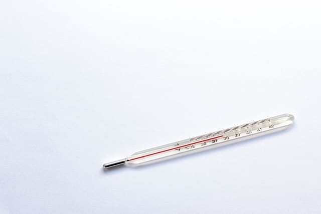An old glass mercury thermometer lying on a white background.