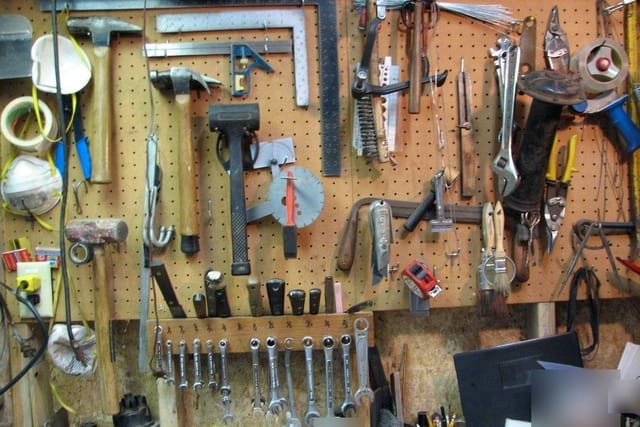 A workshop wall hung with hammers, spanners, pliers, saws and other hand tools.