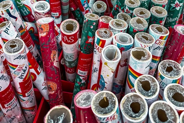 Hundreds of rolls of colourful gift wrap standing upright in a shop display.